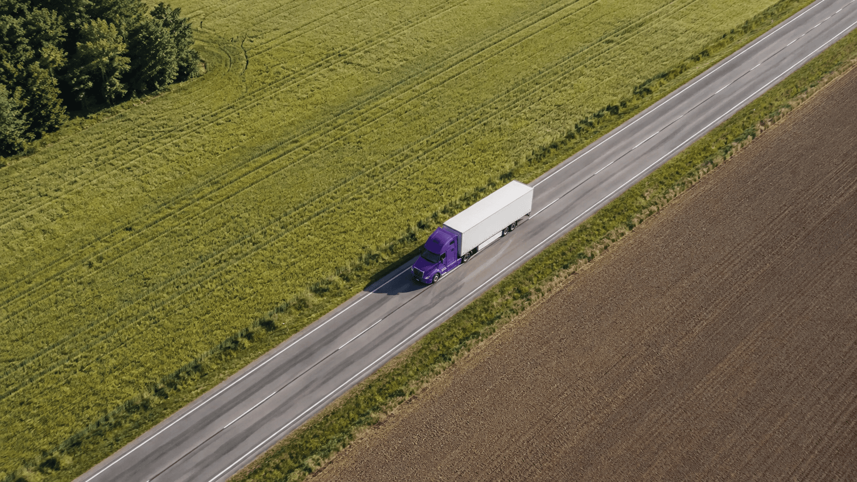 Aerial view of a freight truck on a highway between fields
